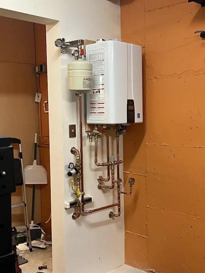 Plumbing technician inspecting water heater connections in Savage